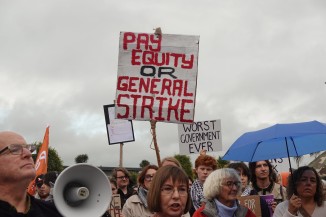 Pay Equity Protest sign above crowd
