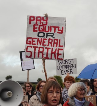 Pay Equity Protest sign above crowd