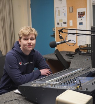 Henderson smiling in a radio production booth