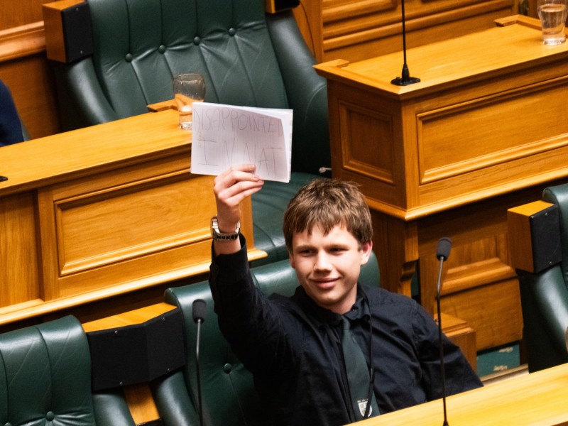 Youth MP Aiden Mill holding up a sigh saying "Disappointed in Nat".